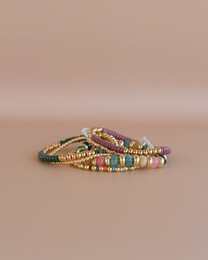 Boho-inspired Jewel Tone Bracelet Set featuring rich teal, pink, green,  and gold tones. Six stretchy bracelets, stacked together for a layered, chic look.